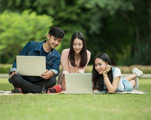 teens looking at laptop computer outside