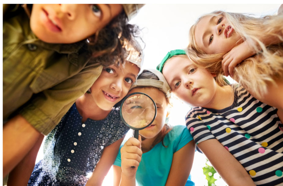 children gathered around a magnifiying glass and looking through it